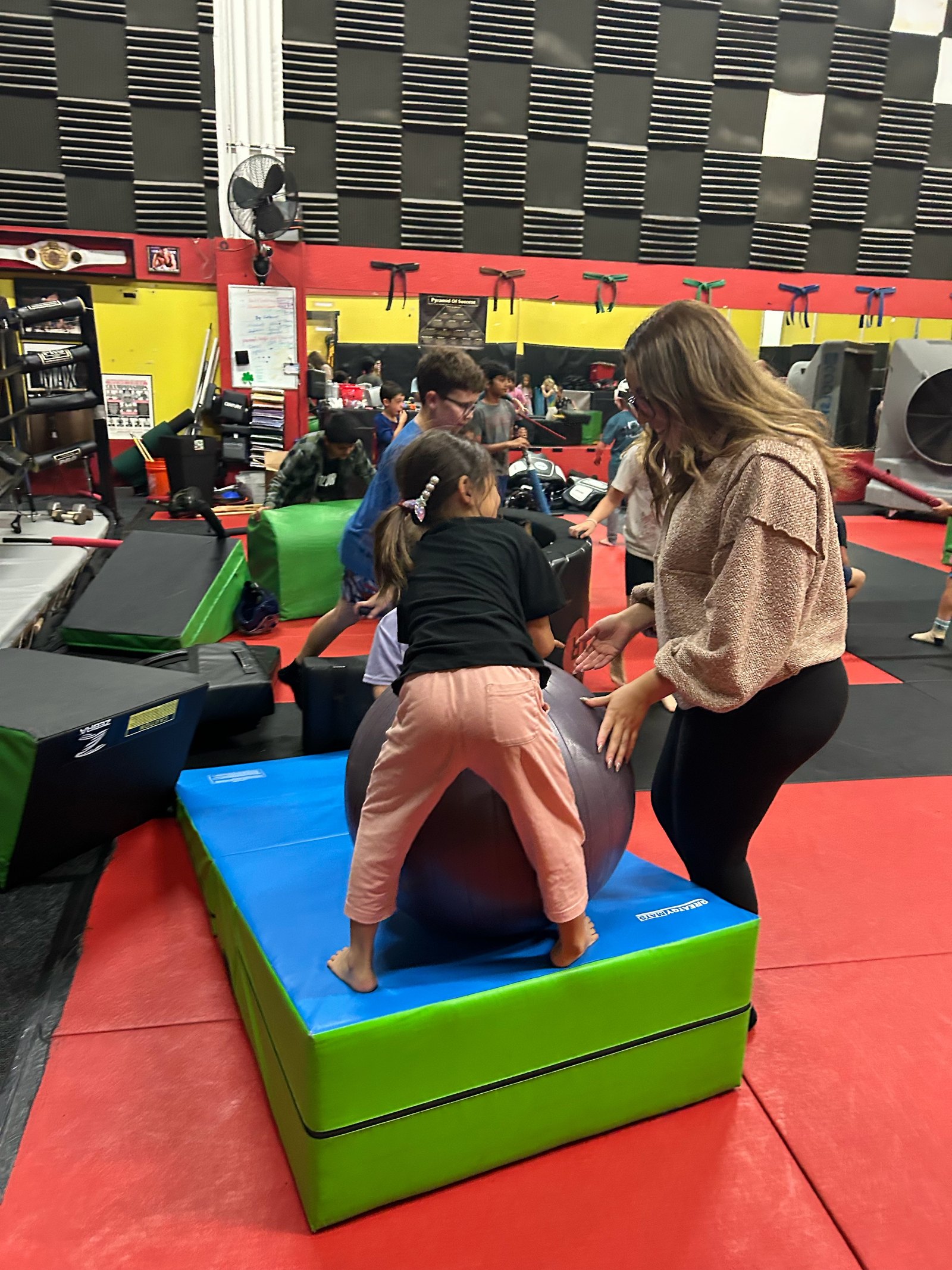 Hala helping a young camper with a movement activity at Blur Martial Arts