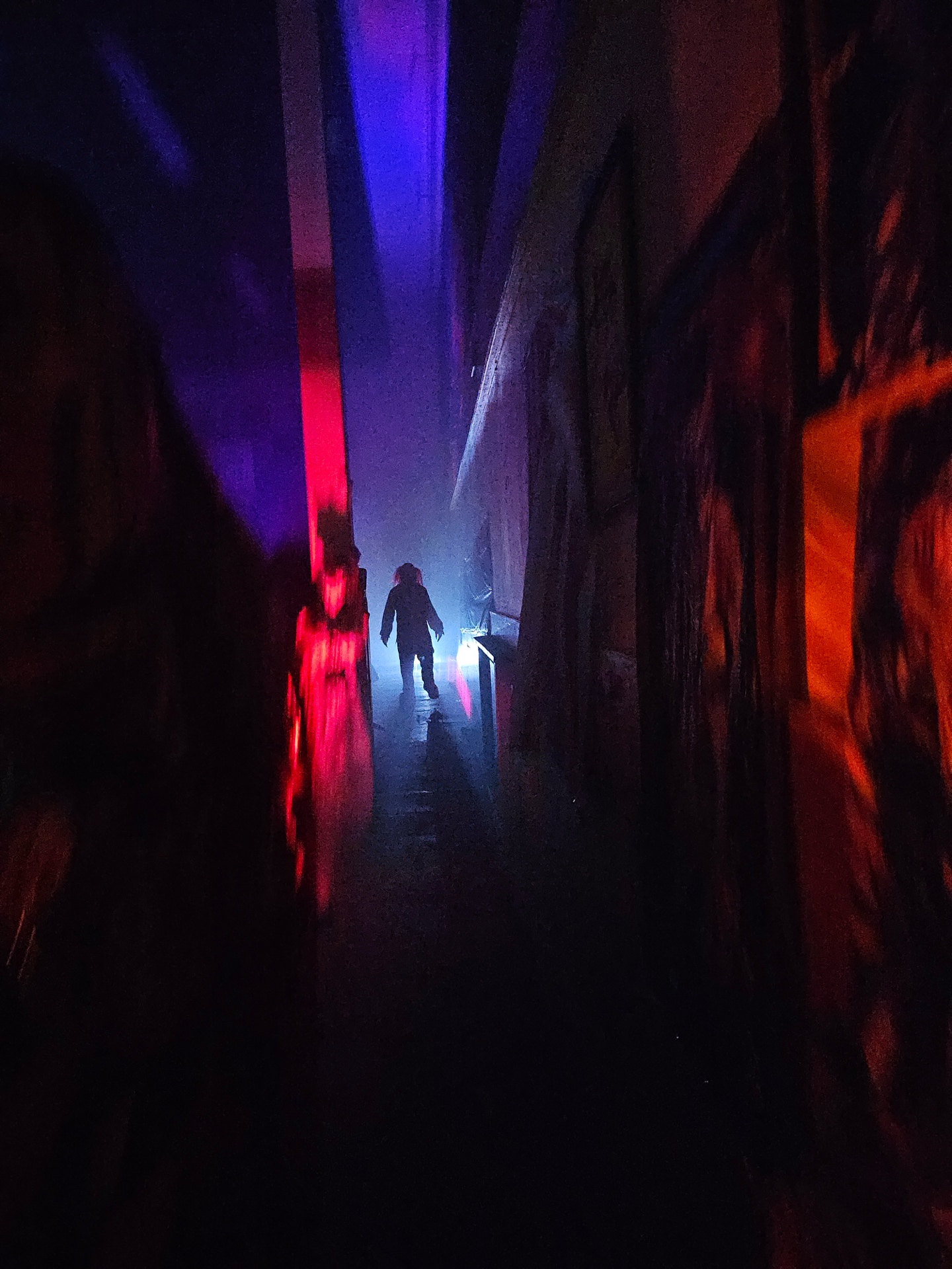 A blue- and red-lit haunted house maze passage